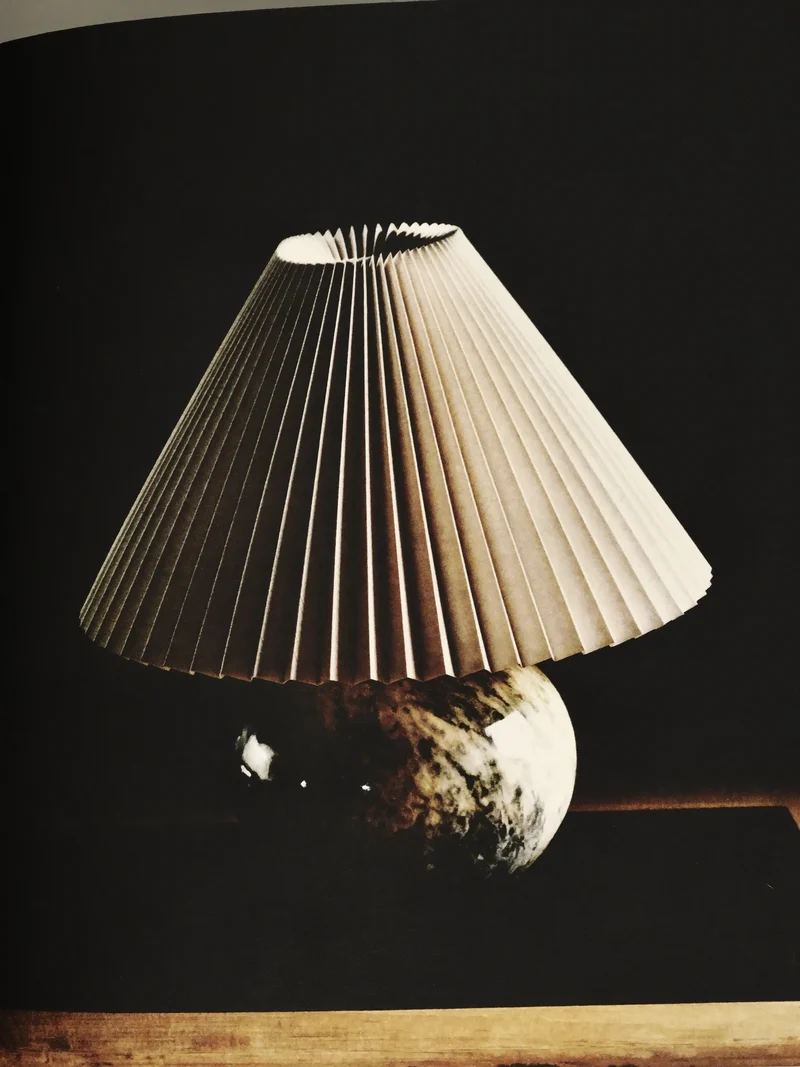 Illustration af en foldet papirlampe med stenfod.